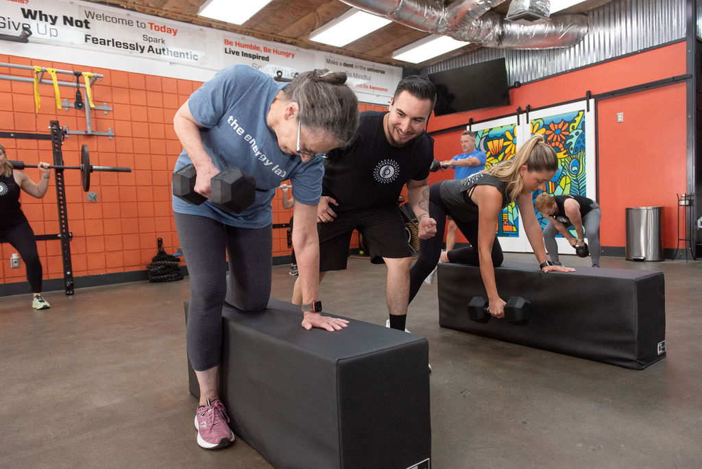 Isaac training a client on how to do a one arm row during a training session at The Energy Lab in Redlands, CA.