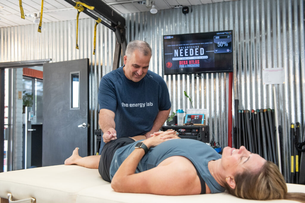 Sean stretching a client's hip flexor while performing a fascial stretch therapy (FST) session at The Energy Lab in Redlands, CA.