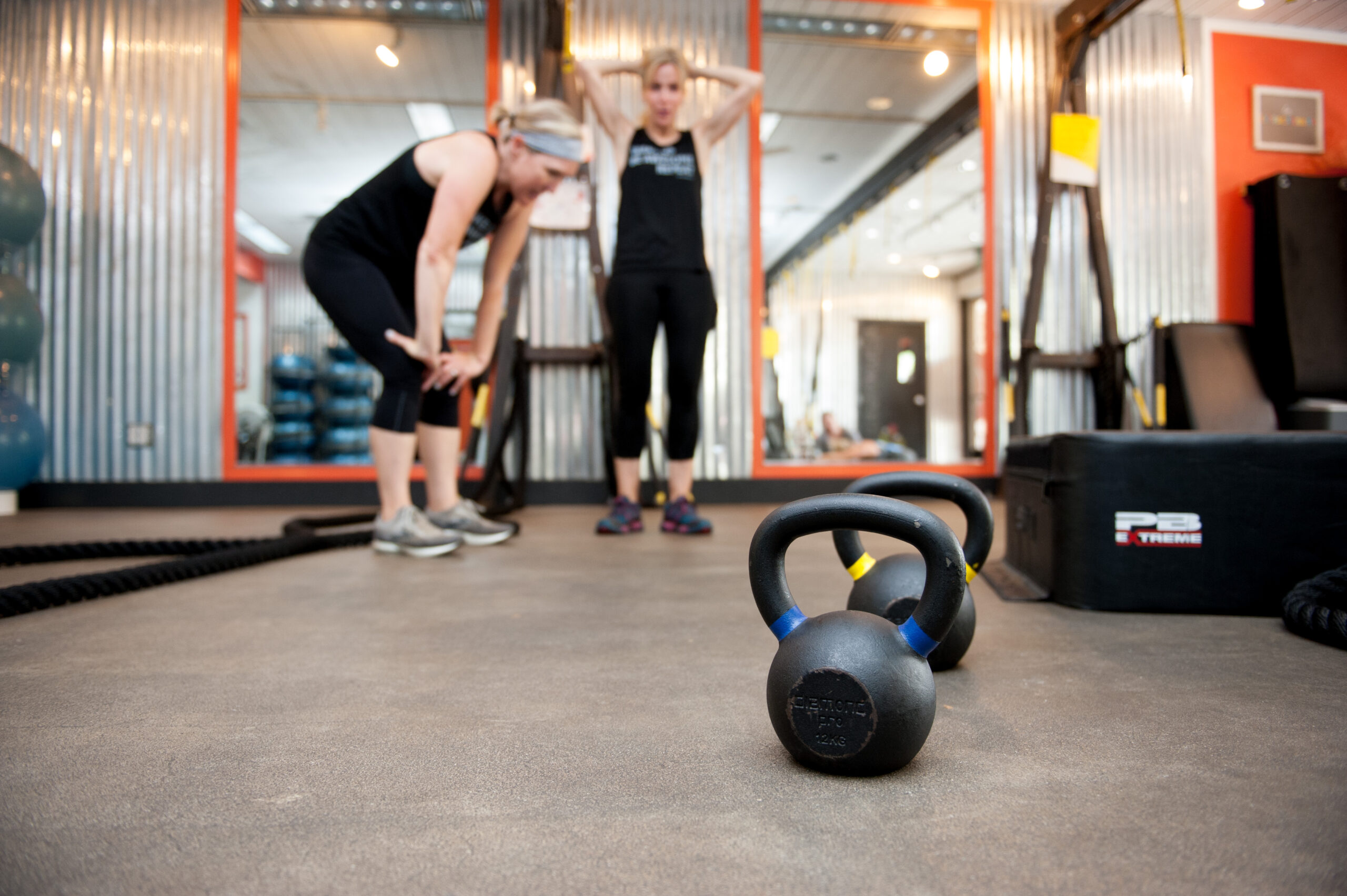 Keri and Teresa pausing in front of kettlebells and a battlerope during a Small Group Personal Training session at The Energy Lab in Redlands, CA.