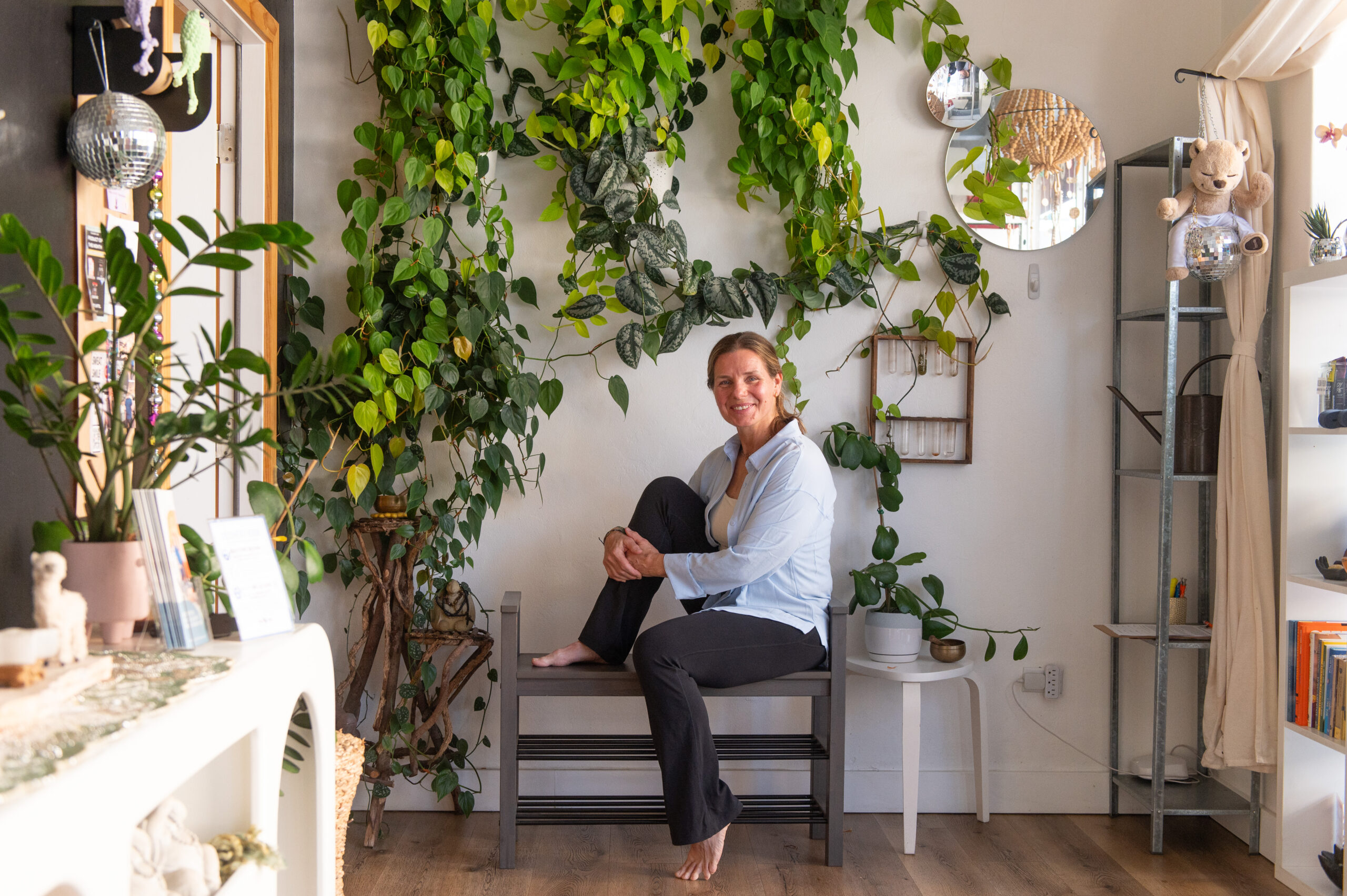 Jill sitting in the lobby of the yoga space in front of plants at The Energy Lab in Redlands, CA.