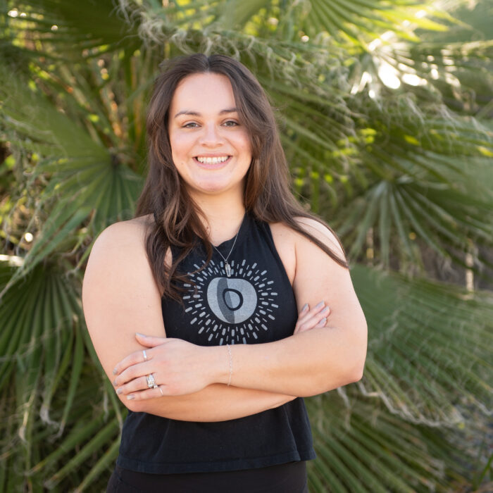 Jacquelyn, personal trainer, yoga instructor, and group fitness coach at The Energy Lab in Redlands, CA, standing outdoors and smiling with arms crossed.