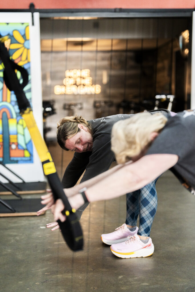 Jill showing a client how to do a stretch on a TRX during a personal training session at The Energy Lab in Redlands, CA.